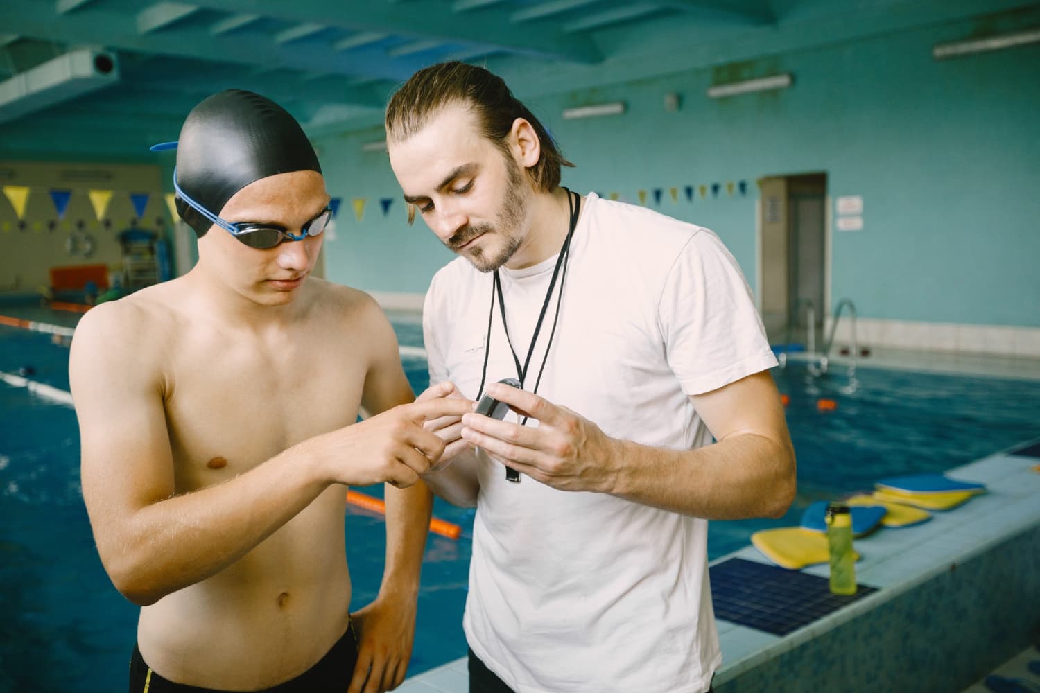 Bild eines Schwimmlehrers der einem Schüler etwas zeigt